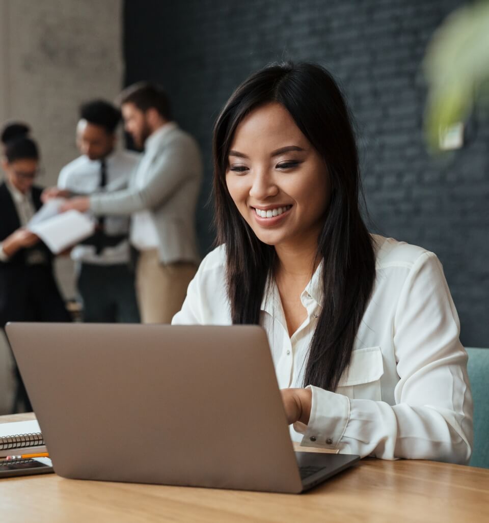 cheerful-young-asian-businesswoman-using-laptop
